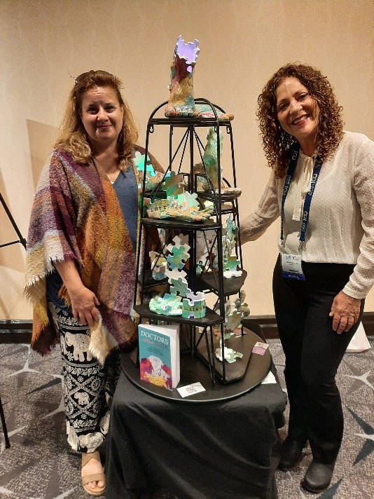 Two women stand in front of a sculpture at the ACR 2023 Annual Meeting