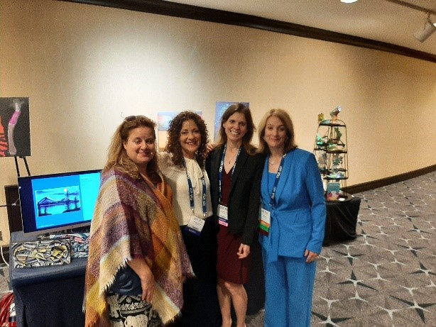 Four women stand together in front of their art displays at the ACR 2023 Annual Meeting