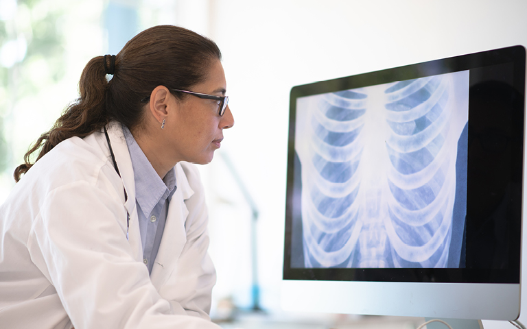 Woman radiologist looking at X-ray on monitor