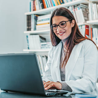 Young female doctor smiling as she works at a laptop