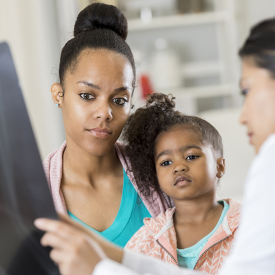 African American mother and daughter reviewing imaging results with female radiologist