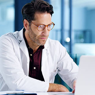 man in the white coat looking at laptop