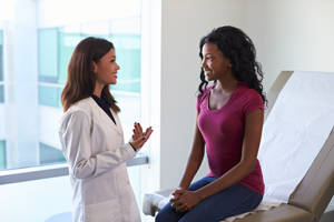 Depicts a young women consulting with her doctor.