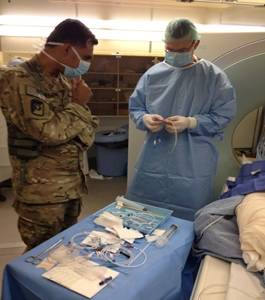 Photo of Mohammad Naeem, MD, FACR, and his surgeon colleague placing a pediatric triple lumen catheter under CT guidance to drain a peri-rectal complex fluid collection in an Afghan soldier.