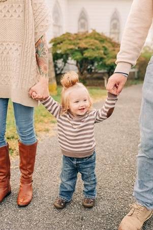 Photo of toddler holding hand of each parent 