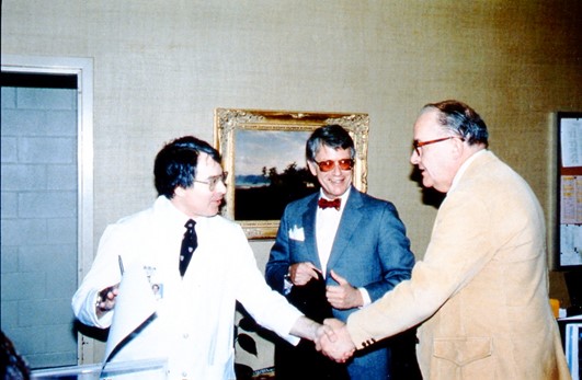 Richard Heller, MD, shakes hands with Paul Lauterbur, PhD as Everette James Jr. MD, FACR looks on at the Vanderbilt University Club, 1980
