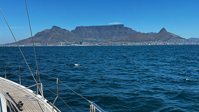 Sailboat arriving in the harbor of Cape Town, South Africa with city and mountains in the background